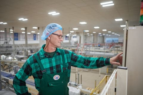 Opérateur en charlotte désignant une ligne de production
